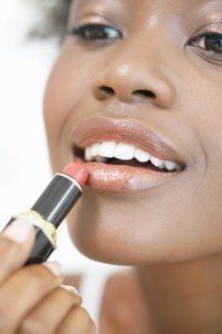 Young woman appying lipstick, smiling, close-up